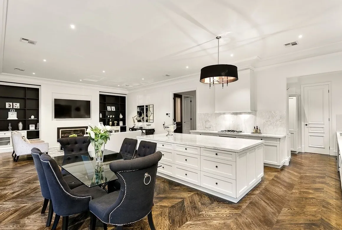 White kitchen and dining area in the completed Camberwell Residence I with black detailing and herringbone timber flooring