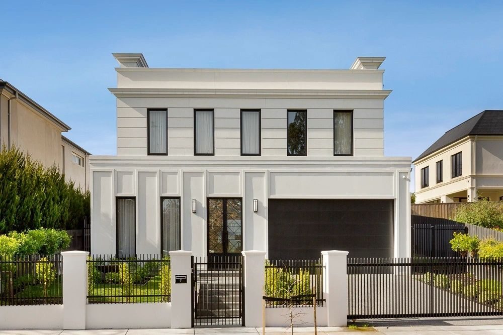 Contemporary white two-storey front façade with black-framed windows, black garage door and black fencing in daylight