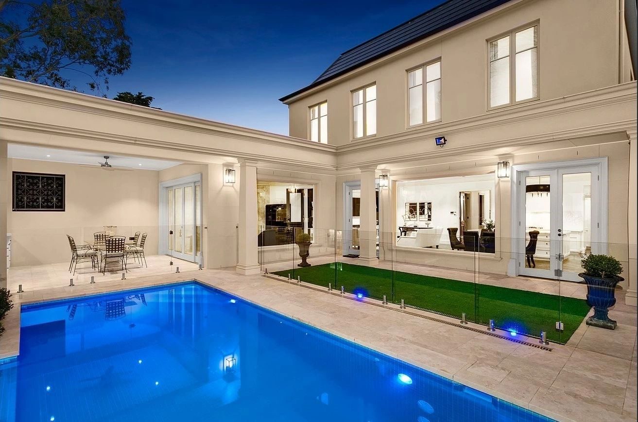 Rear elevation of a residence at twilight with swimming pool and open living areas beyond full-height glazing